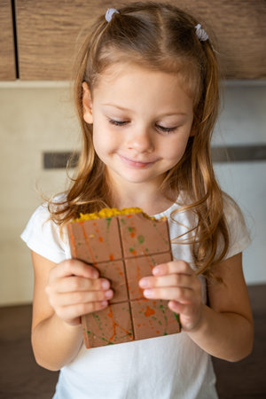 Chocolate with pistachio paste and kataifi dough in hands of little girl. Confectionery handmade sweets at home in the kitchen. High quality photoの写真素材