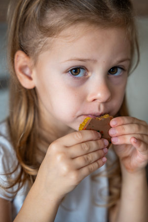 Little girl eating chocolate with pistachio paste and kataifi dough. Confectionery handmade sweets at home in the kitchen. High quality photoの写真素材