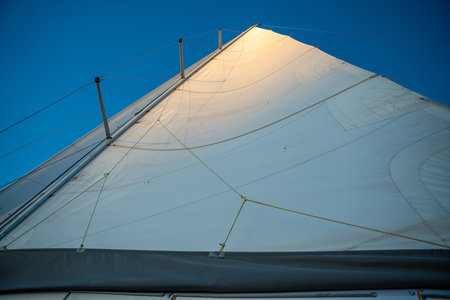 Sunlit top piece of a sail of a sailing yacht in the wind sailing on the sea . High quality photoの写真素材