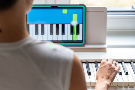 Close up view of young woman learning to play the keyboard at home using an interactive app. Using mobile apps for self-study concept. High quality photoの写真素材