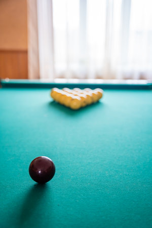 Initial billiard ball arrangement with white balls in a triangle and red cue ball ready for the break. Concept of indoor recreation and personal hobby space. High quality photoの写真素材