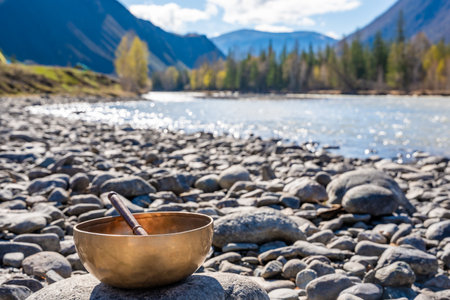 Tibetan singing bowl placed on river stones near mountain water in Altai. Concept of grounding energy, sacred silence, and spiritual resonance in wild nature. High quality photoの写真素材