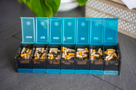Weekly pill organizer with labeled compartments for daily medication doses. Concept of health...