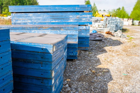 Stacks of blue metal formwork panels stored outdoors at a construction site. Concept of reusable...