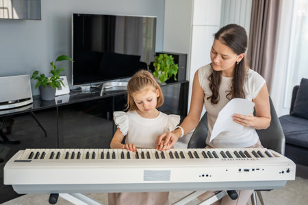 Individual piano lesson for a young child at home in the living room. Concept of early childhood development through personalized music education. High quality photoの写真素材