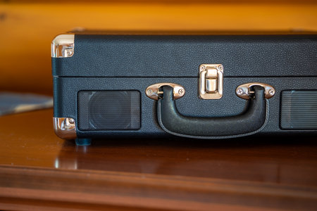 Closed vintage-style record player in suitcase design on wooden table. Retro audio equipment ready to play vinyl in cozy home setting. High quality photoの写真素材