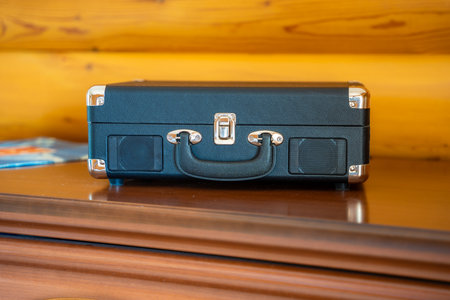 Closed vintage-style record player in suitcase design on wooden table. Retro audio equipment ready to play vinyl in cozy home setting. High quality photoの写真素材