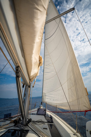 Full white sails blown by the wind against blue sky during sailing near Croatia. Symbol of movement,...