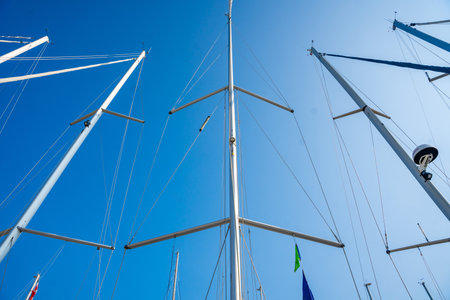 View from below of multiple sailboat masts rising into the sky in the marina on Hvar Island,...