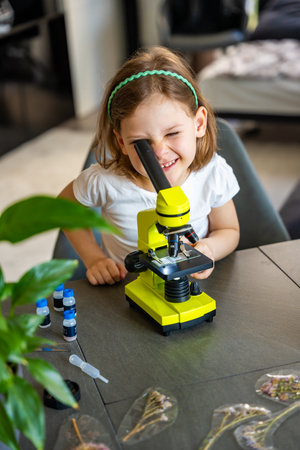 Little girl looking through a microscope. Concept of curiosity and early scientific exploration....