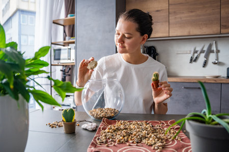 Young woman looking at small cacti while planning the arrangement of a future terrarium. Concept of creative thinking, eco-friendly design and mindful connection with nature. High quality photoの写真素材