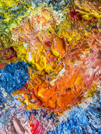 Detailed view of oil paints blended on an artist palette. Focus on warm yellow and orange tones with...