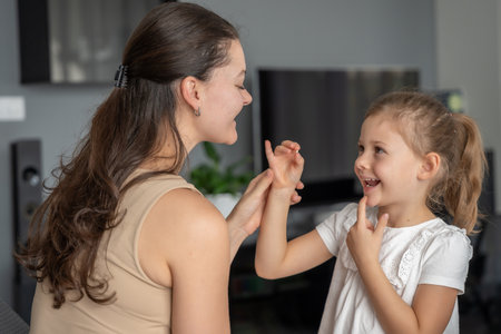 Little girl proudly shows her first lost baby tooth to her mom. Concept of childhood milestones, family bonding and emotional parenting moments. Focus on tooth. High quality photoの写真素材