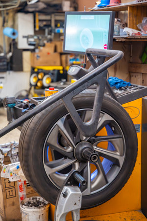 Car wheel rotating on a balancing machine during seasonal tire service at an auto workshop. Essential step to ensure smooth driving and tire longevity before winter installation. High quality photoの写真素材