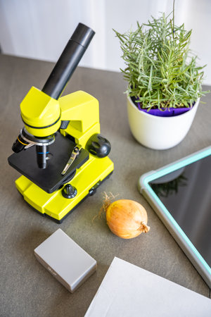 Yellow microscope, tablet, and experiment box on a desk. Educational science kit for kids learning microscopy and biology at homeの写真素材