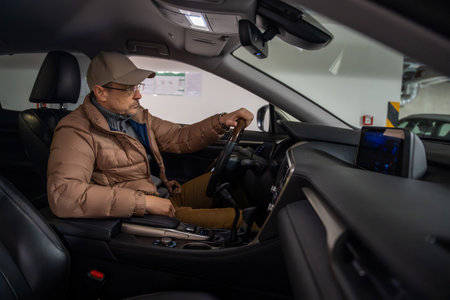Man in driver seat setting steering wheel in underground parking. Preparation for trip and commuting...