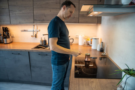 Man preparing meal at stove in modern kitchen. Home cooking and everyday life.の写真素材