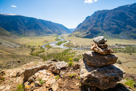 Stone cairn on mountain with view of Chulyshman valley and river in Altai Russia Symbol of hiking and nature exploration. High quality photoの写真素材