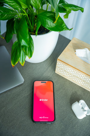 Prague, Czech Republic - February 19, 2026: Smartphone with Tinder app open lying on desk in home workspace interior. Online dating platform and modern digital relationship search conceptのeditorial素材