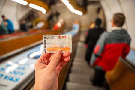 Prague, Czech republic - January 16, 2026: Passenger holding PID public transport ticket on escalator inside Prague metro station. Urban commuting in Czech Republicのeditorial素材