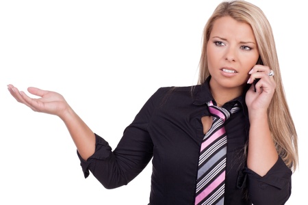 Attractive young blonde woman explaining something on her mobile gesturing with her hand and frowning as she tries to understand somethingの写真素材