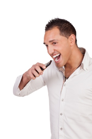 Ecstatic good looking young man holding a mobile and laughing after receiving a call with good news, studio half body portrait isolated on whiteの写真素材
