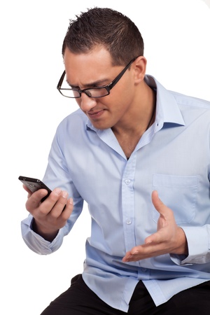 Studio shot over white of a young man who is exasperated by the text message he has just receivedの写真素材