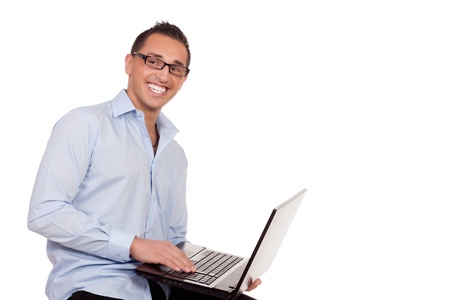 Enthusiastic businessman using a laptop balanced on his arm as he sits on a stool conceptual of the wireless connectivity and portability of the computer as a business tool isolated on whiteの写真素材