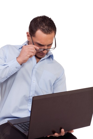 Man battling to read his laptop screen lowering his glasses by the frame so that he can see better due to the short focal length as he is handholding the computerの写真素材