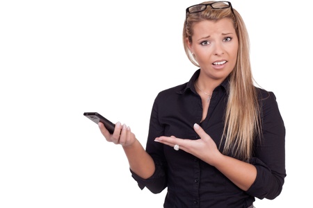 Confused woman holding a smartphone and pointing to it with the other hand as she looks questionningly at the camera, upper body studio portrait on whiteの写真素材