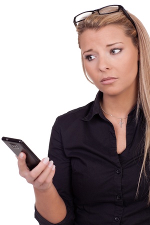 Worried woman looking at her mobile as she waits anxiously for a call, studio portrait isolated on whiteの写真素材