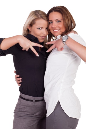 Two playful attractive women standing in a close intimate embrace making V-signs with their fingers, three quarter studio portrait on whiteの写真素材