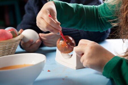 Cropped view image of the hands of a young girl carefully painting traditional Easter eggs in colourful patternsの写真素材