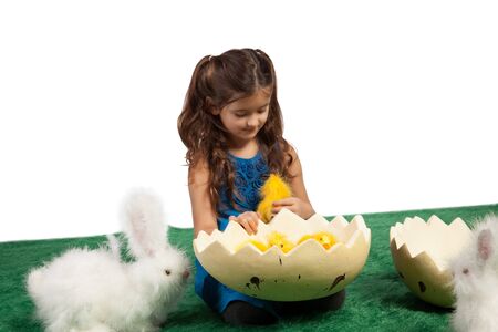 Easter theme with young girl with toy bunnies and an egg shape with chicks inside の写真素材