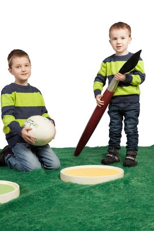 Easter theme with two young boys with a huge brush, colour palette and egg の写真素材