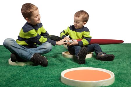 Two young boys pulling at a big brush while both sitting in two big palettes の写真素材