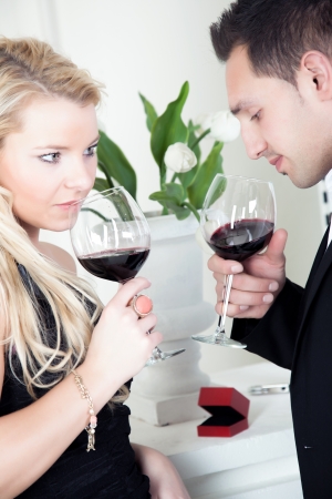 Tender young couple celebrating together holding glasses of red wineの写真素材