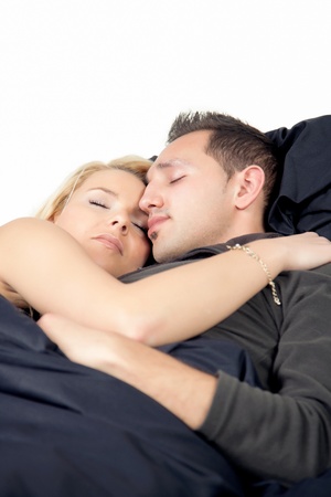 Young couple enjoying sweet dreams as they lie close together with their arms around each other having a peaceful sleepの写真素材