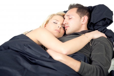 Young couple sleeping in bed entwined in each others arms as they enjoy happy dreams and a restful sleepの写真素材