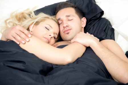 Affectionate couple enjoying a blissful sleep as they lie in bed entwined in each others armsの写真素材