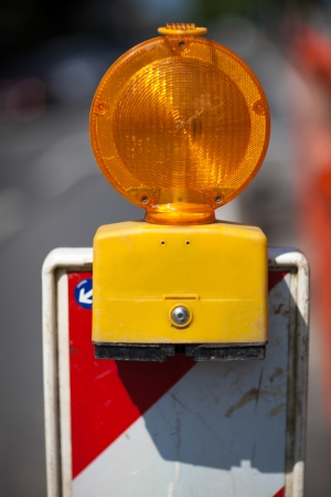 Closeup of a temporary amber warning light set up at the side of a road warning motorists of roadworks and maintenanceの写真素材