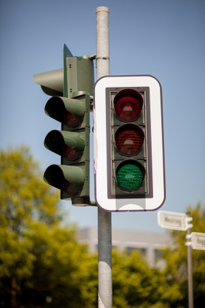 Traffic light mounted on a pole in a town against blue sky with green light illuminated allowing cars to proceedの素材 [FY31020274471]