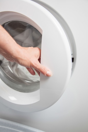 A Lady is closing the door before the washing program starts の写真素材