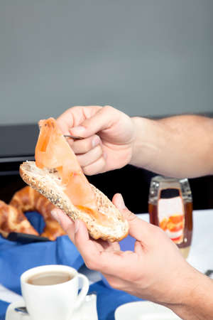 Hands of a man seated at a table selecting sliced cold ham for his buttered wholewheat rollの写真素材