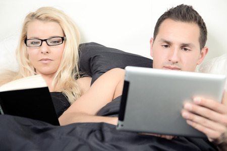 A couple is lying in there bed while working の写真素材
