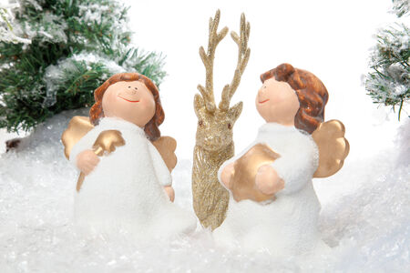 Two angles are guarding the golden reindeer in a snow covered winter landscape の写真素材