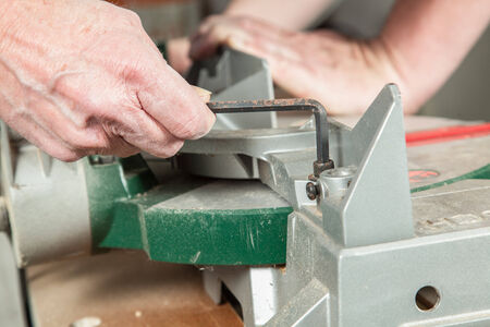 A man is using an Allen key to fit the screw at the buzz saw の写真素材