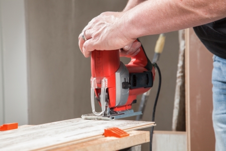 A man is sawing a piece of Laminate with a jigsaw の写真素材