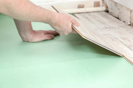 A man is trying to fit a piece of laminate to an other one の写真素材