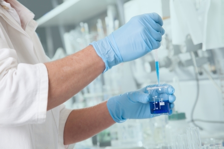 A Chemist retrieve samples from a blue Liquid の写真素材